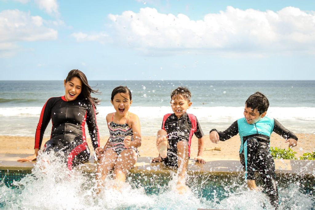 Family with children splashing and playing in ocean waves at a New England beach